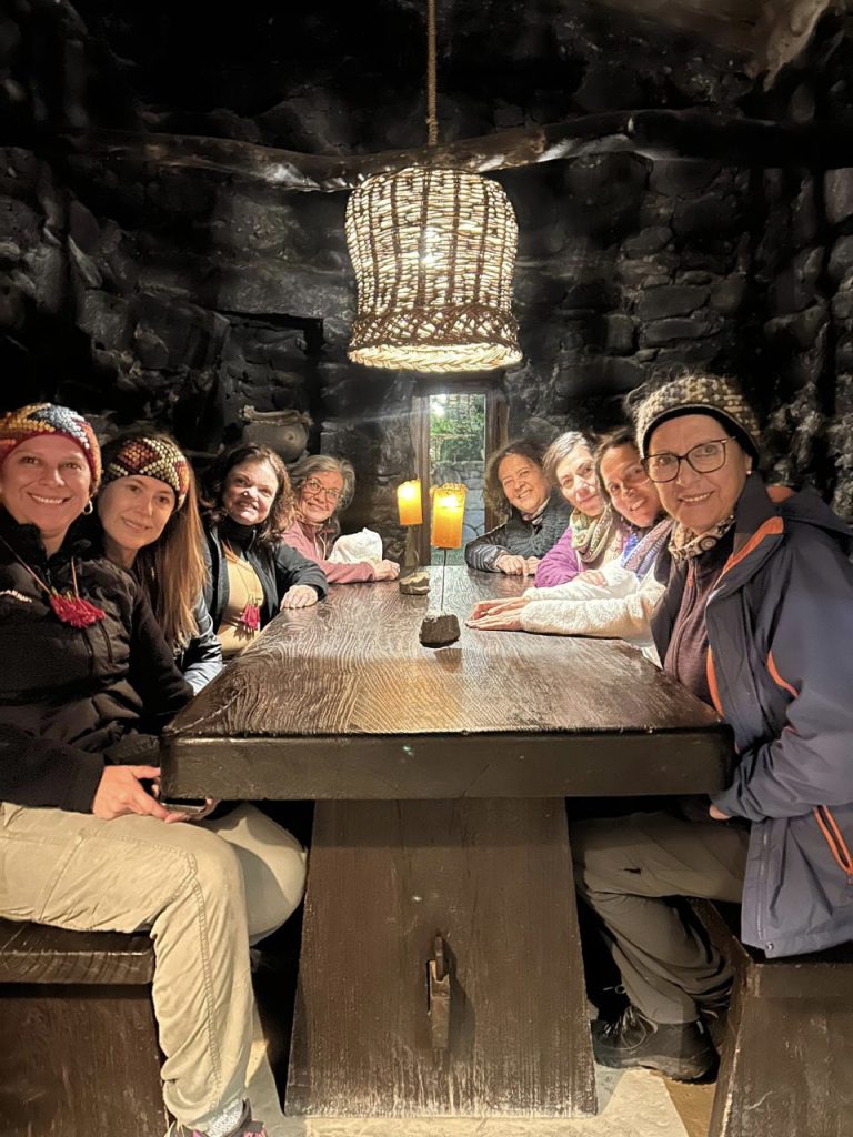 Grupo de mujeres sentadas a una mesa de madera en un restaurante con muros de piedra