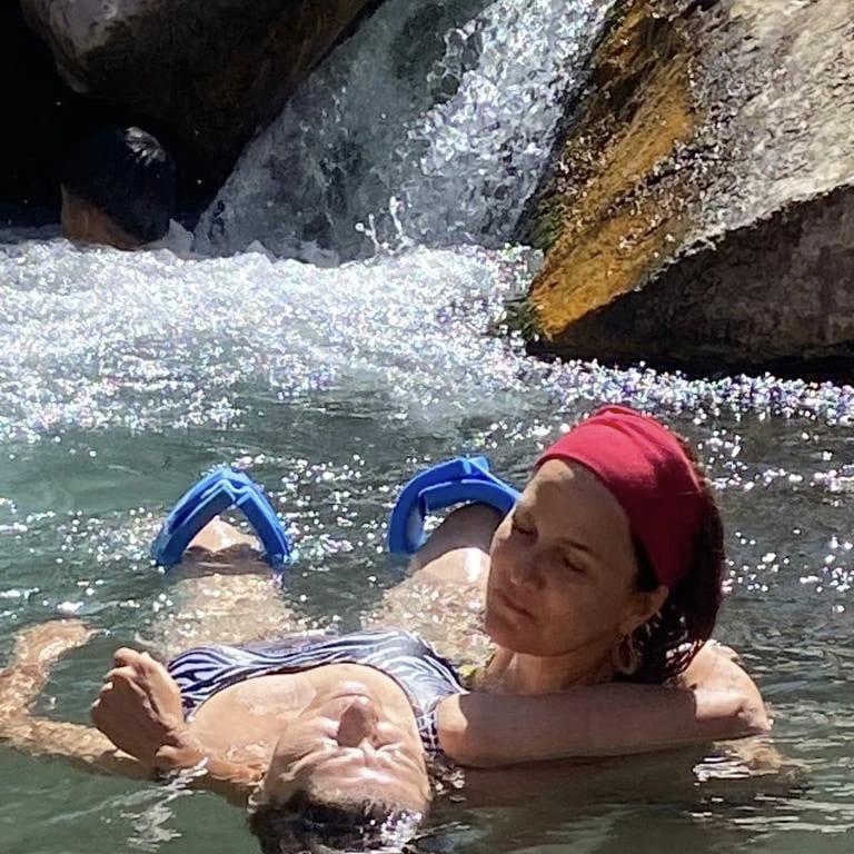 Mujer relajándose en una poza de agua termal con una tabla de flotación