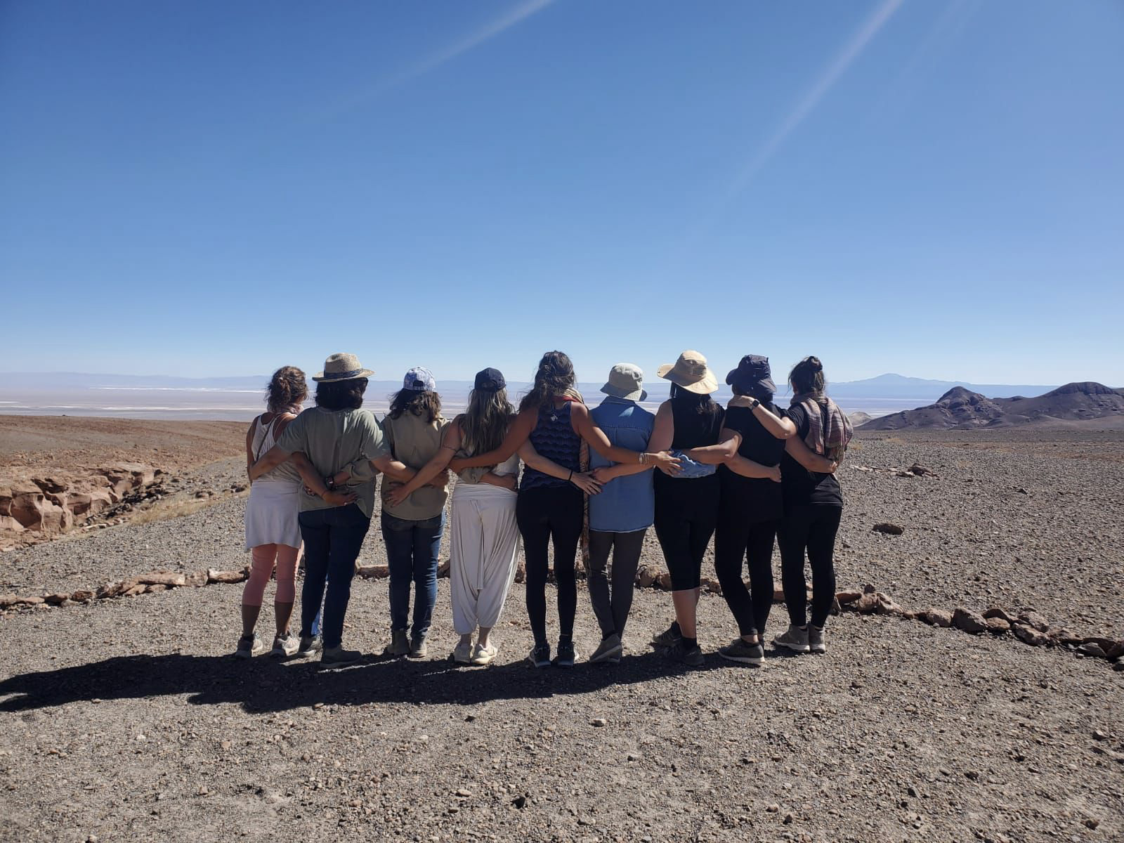 Grupo de mujeres abrazadas de espaldas frente al desierto de Atacama