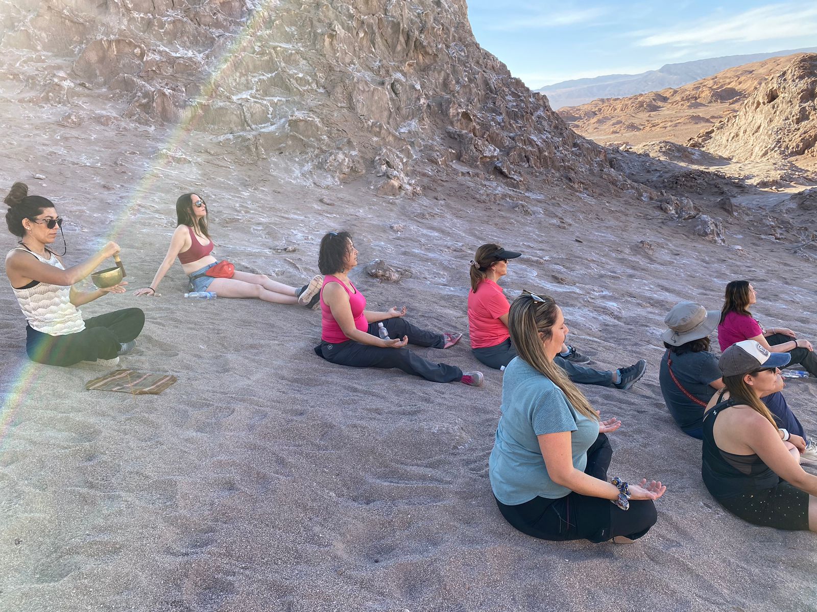 Grupo meditando en el desierto con un cuenco tibetano al atardecer