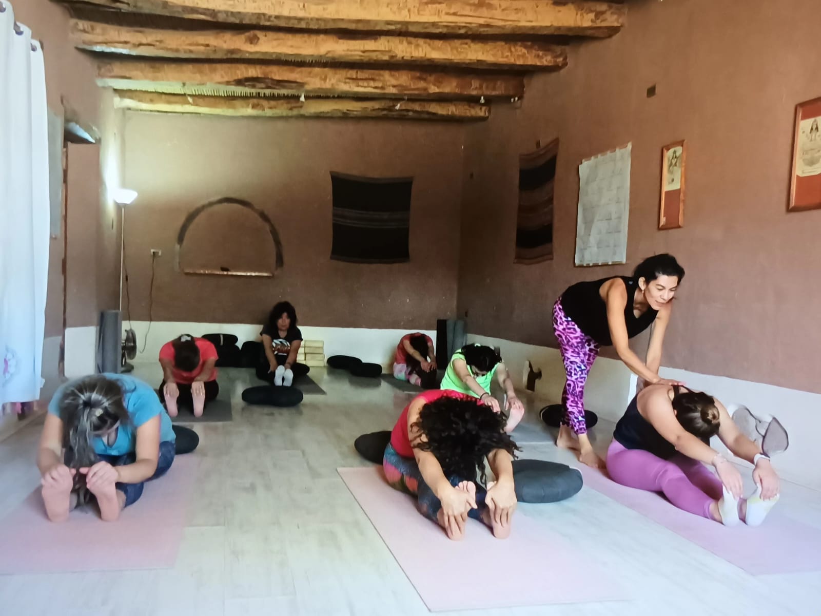 Grupo practicando yoga en una sala con vigas de madera, guiado por Lore de Nordenflycht