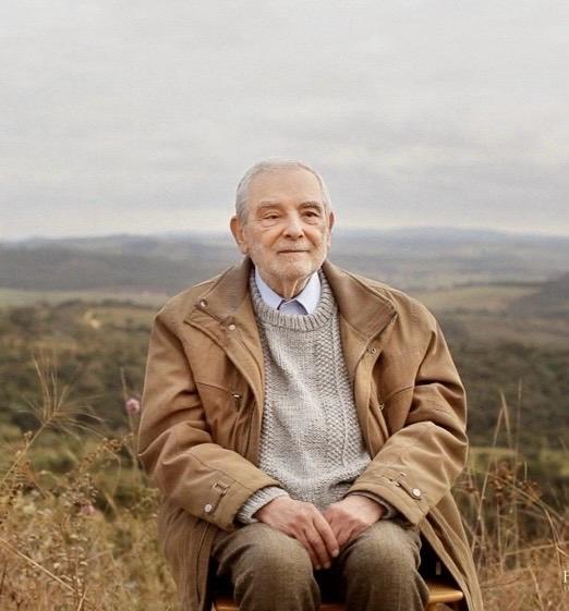 José Trigueirinho sentado al aire libre, con un paisaje de cerros al fondo