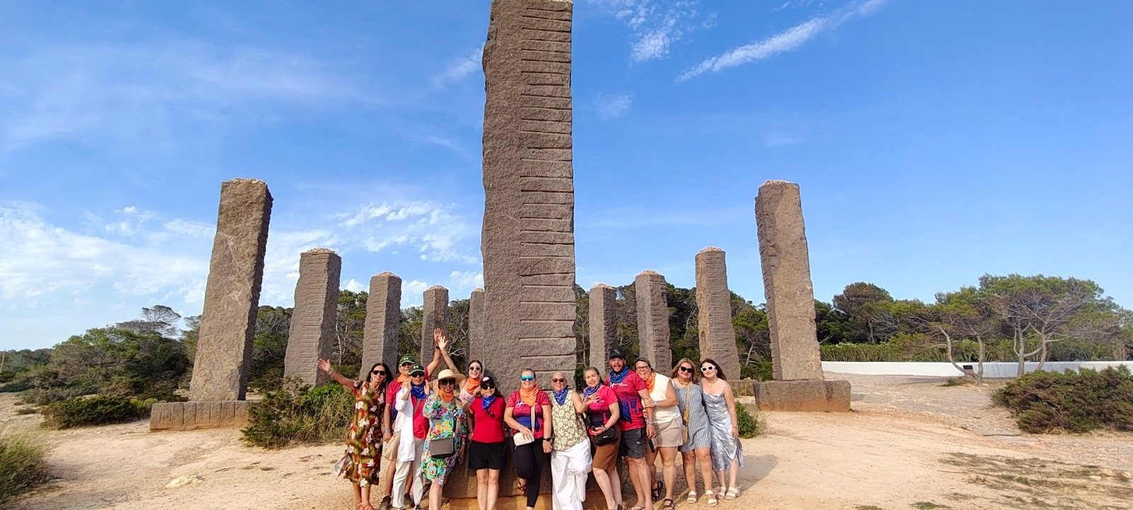 Grupo de viajeros posando frente a los grandes monolitos de piedra del Reloj Solar de Ibiza